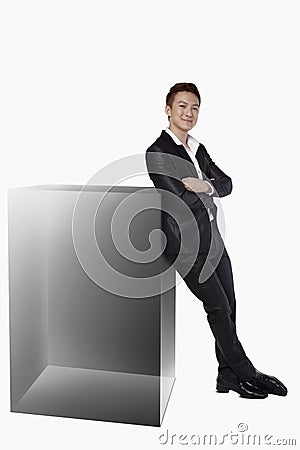 Businessman leaning against a square cube. Conceptual image Stock Photo