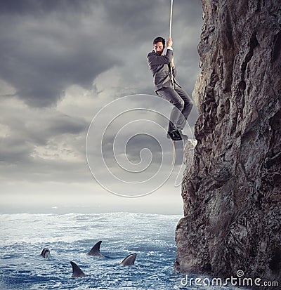 Businessman is likely to fall into the sea with sharks. concept of problems and difficulty in business Stock Photo