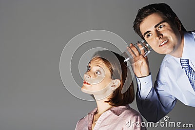 Businessman Listening Through Glass To Woman's Head Stock Photo