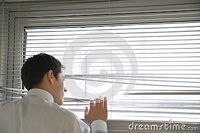 Businessman Looking Through Blinds Stock Photo