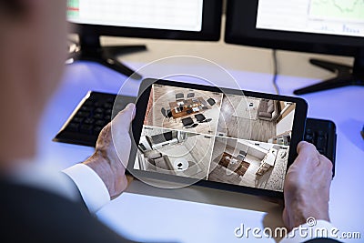 Businessman Looking At CCTV Camera Footage On Digital Tablet Stock Photo