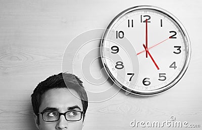Businessman Looking At Clock On Wooden Wall Stock Photo