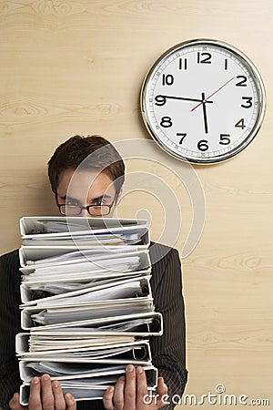 Businessman Looking At Clock On Wooden Wall Stock Photo