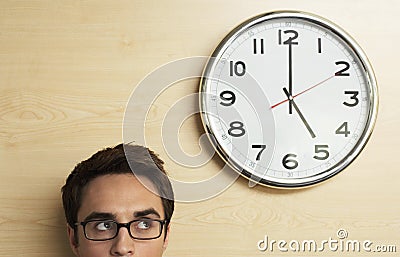 Businessman Looking At Clock On Wooden Wall Stock Photo