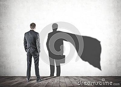 Businessman looking at his superman shadow Stock Photo