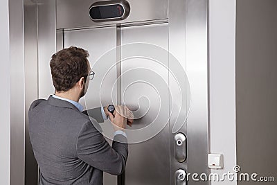 Businessman looking at his watch while waiting for the elevator Stock Photo