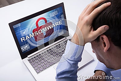 Businessman Looking At Laptop With Ramsomware Word On The Screen Stock Photo