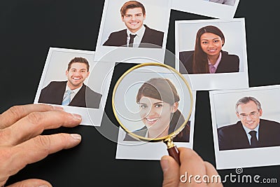 Businessman looking at photograph through magnifying glass Stock Photo