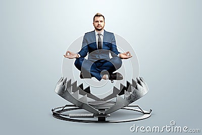 A businessman in the lotus position levitates over a bear trap. Concept of problem solving, failure, crisis, crisis management Stock Photo