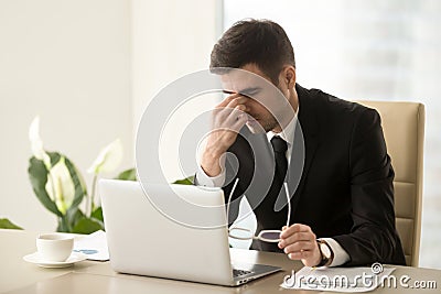 Businessman massaging nose bridge, holding glasses, eye strain, Stock Photo