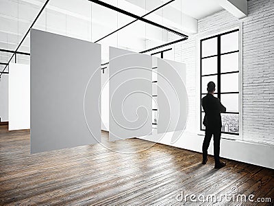 Businessman Modern museum expo loft interior.Open space studio.Empty white canvas hanging.Wood floor,bricks wall Stock Photo