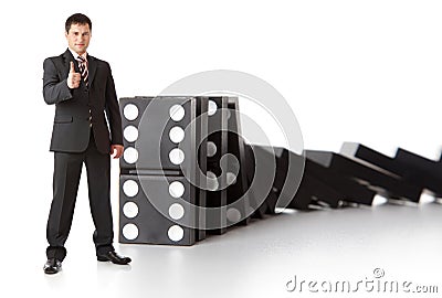Businessman near a stack of dominoes Stock Photo