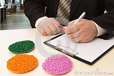 Businessman in the office signs a contract for the supply of plastic granules for industry. Plastic raw material in granules Stock Photo