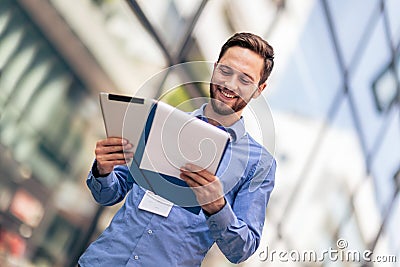 Businessman is outside and he has to work so he is using tablet and worksheets Stock Photo