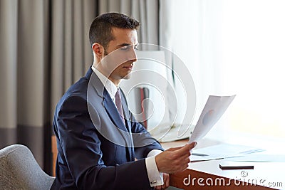 Businessman with papers working at hotel room Stock Photo