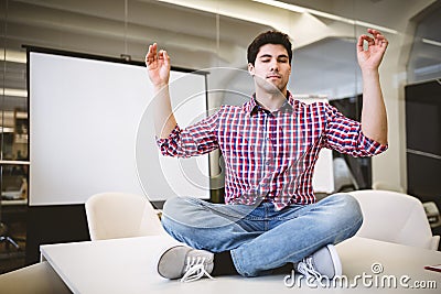 Businessman performing yoga in meeting room Stock Photo