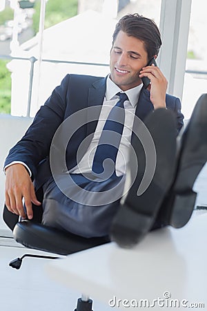 Businessman on the phone relaxing with his feet on his desk Stock Photo