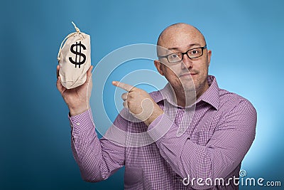 A businessman in a piked shirt pointing with the index finger on a sack with dollars Stock Photo