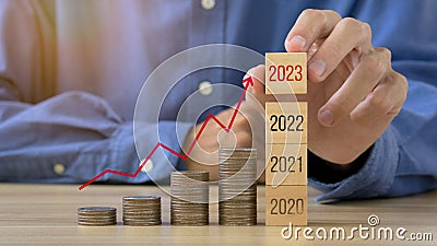 Businessman planning 2023 business growth on desk with virtual hologram chart graph.Old wooden of 2022 to new wooden of 2023.New Stock Photo