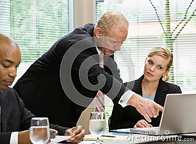 Businessman pointing to female co-workerï¿½s laptop Stock Photo