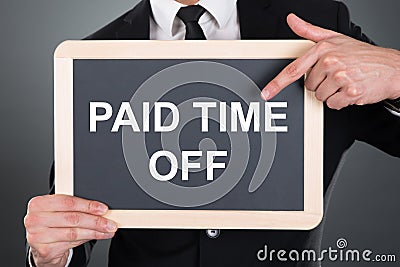 Business Man Pointing At Paid Time Off Text On Slate Stock Photo