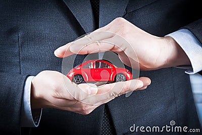 Businessman protect with his hands a red car, concept for insurance, buying, renting, fuel or service and repair costs Stock Photo