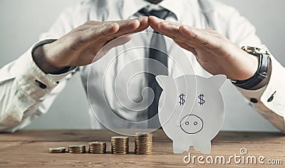 Businessman protect paper piggy bank and coins. Saving money concept Stock Photo
