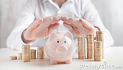 Businessman protect piggy bank and coins. Saving money Stock Photo