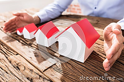 Businessman Protecting The House Models With Hands Stock Photo