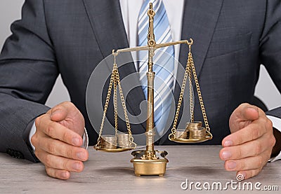 Businessman protecting justice scale with coins Stock Photo