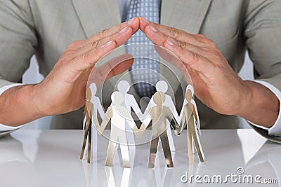 Businessman Protecting Paper Team On Desk Stock Photo