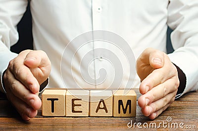 Businessman protects wooden blocks with the word Team. Care for employees. Security and safety in a business team. Human resources Stock Photo