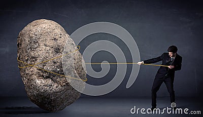 Businessman pulling huge rock with a rope Stock Photo