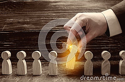 A businessman pulls a glowing golden man figure out of a gray crowd. The concept of search workers for hiring, promotion. Business Stock Photo