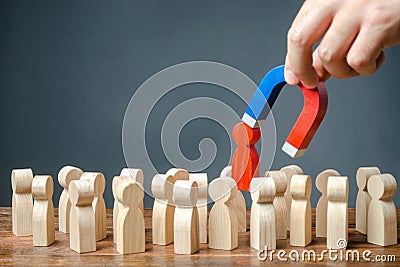 businessman pulls out a red figure of a man from the crowd with the help of a magnet. Increase team efficiency, productivity. Stock Photo