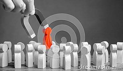 businessman pulls a red figure out from the gray crowd with a magnet. Increase team efficiency, productivity. leader manages Stock Photo