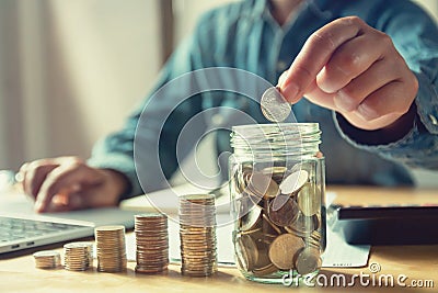 businessman puting coins into jug glass. concept saving money an Stock Photo