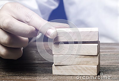 Businessman puts wooden blocks. Business management concept. Planning and strategy. Setting and achieving goals. Business Stock Photo