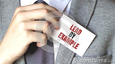 Businessman putting a card with text Lead by example in the pocket Stock Photo