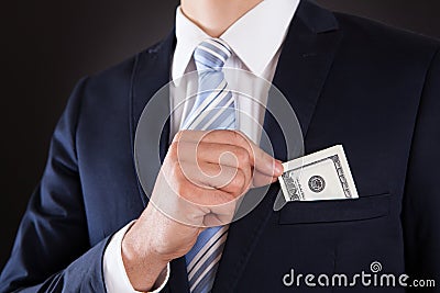Businessman Putting Money In Pocket Stock Photo