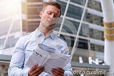 Businessman reading newspaper feeling serious while standing in urban background. men holding newspaper in his hand with Stock Photo