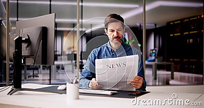 Businessman Reading Newspaper At Office Desk Stock Photo