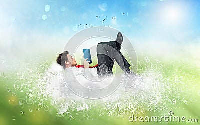 Businessman reads a book over a cloud made of letters. Concept of relax and imagination Stock Photo