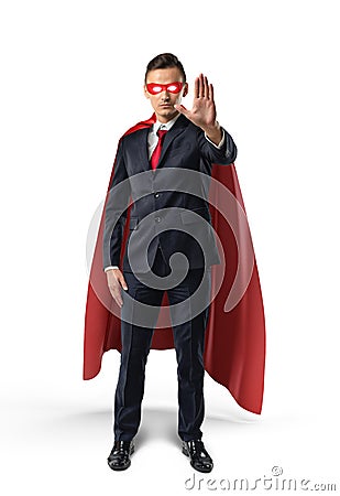 Businessman in a red cape and red eye mask with one hand raised in warning on white background. Stock Photo