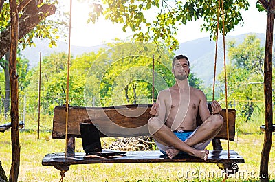 Businessman relaxes after working on laptop sitting in lotus pose outdoors. Stock Photo