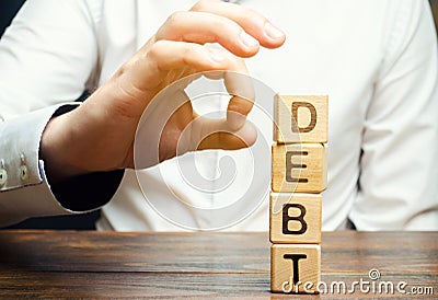 Businessman removes wooden blocks with the word Debt. Reduction or restructuring of debt. Bankruptcy announcement. Refusal to pay Stock Photo