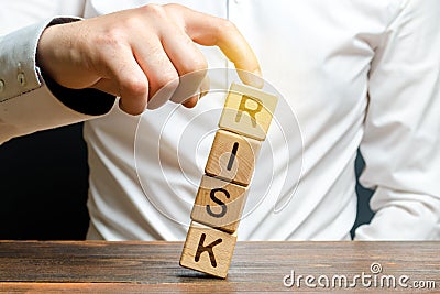 Businessman rescues with his finger a tower of cubes with the word Risk from falling Risk management, cost assessment, business Stock Photo