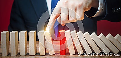 Businessman restarts the process of falling dominoes. Start work after stopping. Continuation of working, obstacle avoidance. Stock Photo