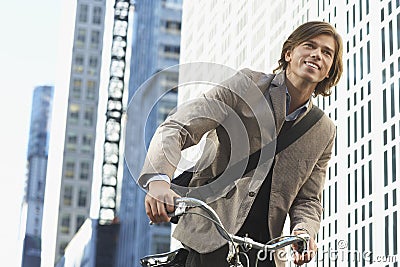 Businessman Riding Bicycle In Downtown District Stock Photo
