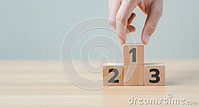 Businessman`s hand chooses number 1 on the podium with number 2, 3 of wooden building blocks. Stock Photo